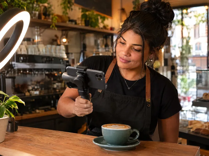 Empreendedora gravando vídeo com o celular no próprio café